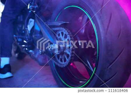 Sport motorcycle wheel view from back in neon light and smoke 111618406
