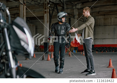 Student motorcyclist and instructor discussing rout of future exam race Student motorcyclist and instructor discussing rout of future exam race 111618422