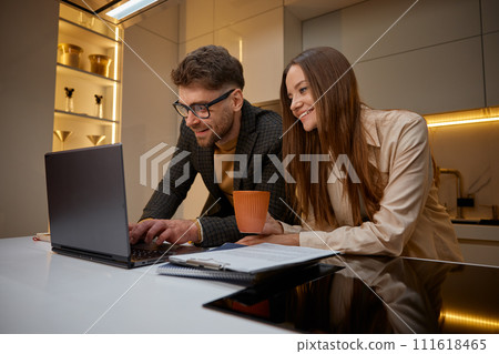 Young family using laptop on kitchen, husband helping loving wife with project Young family using laptop on kitchen, husband helping loving wife with project 111618465