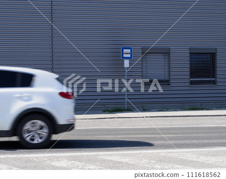 Bus stop and road with a white car in motion Bus stop and road with a white car in motion 111618562