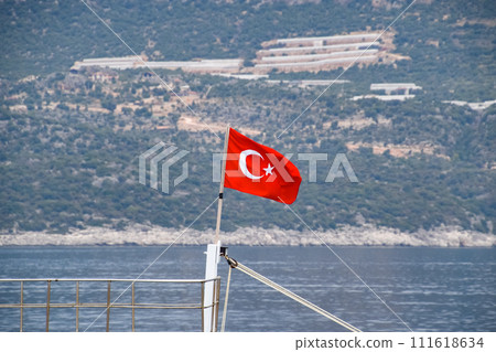The flag of Turkey flutters in the wind on the deck of pleasure yacht. The flag of Turkey flutters in the wind on the deck of pleasure yacht. 111618634