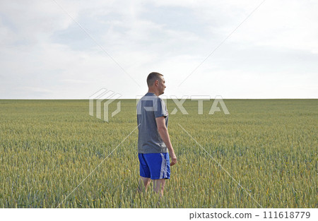 a male farmer stands among a field of ripening wheat harvest 111618779