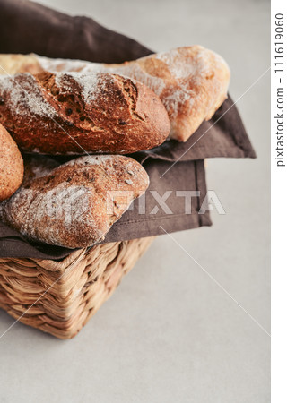 Assorted bakery products including loafs of bread,  baguette and rolls in basket 111619060