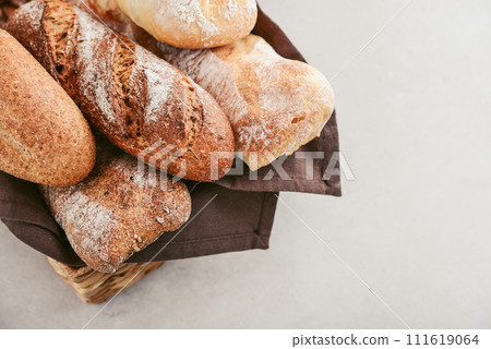 Assorted bakery products including loafs of bread,  baguette and rolls in basket 111619064