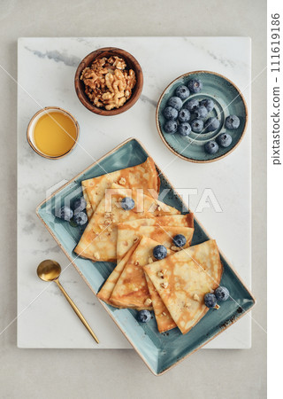 Thin pancakes, homemade crepes on a plate with blueberry Thin pancakes, homemade crepes on a plate with blueberry 111619186
