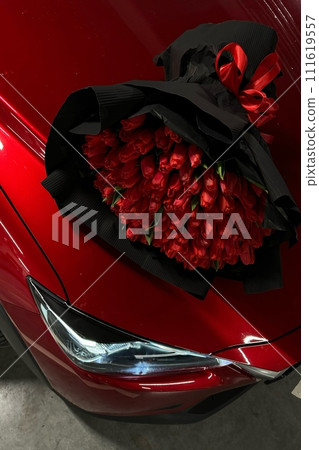 A large bouquet of bright red tulips on a red car 111619557