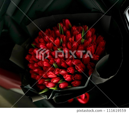 A large bouquet of bright red tulips on a red car 111619559