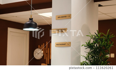 Empty stylish business accommodation lobby interior with deluxe spa center, conference room, and restaurant amenities. Close up of hotel facilities plaque signs on resort foyer wall 111620261