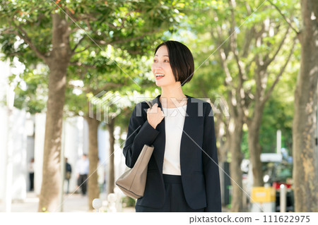 一個30多歲的女人穿著西裝在新綠色微笑 一個30多歲的女人穿著西裝在新綠色微笑 111622975