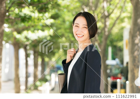 一個30多歲的女人穿著西裝在新綠色微笑 一個30多歲的女人穿著西裝在新綠色微笑 111622991