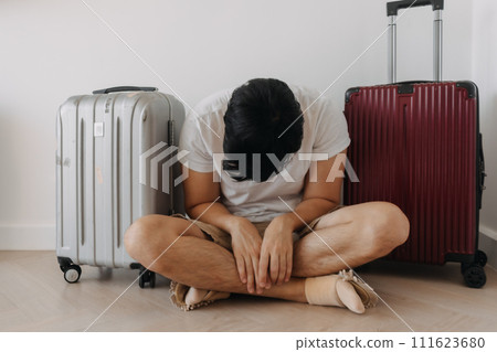 Sad disappointed man sit with his luggages as his traveling trip plan has been cancelled. 111623680