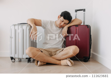 Sad disappointed man sit with his luggages as his traveling trip plan has been cancelled. 111623681