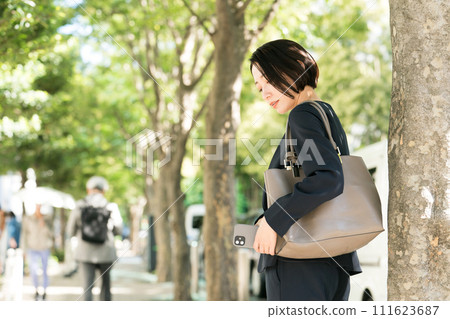 穿著西裝的女人用智慧型手機秘密拍照 穿著西裝的女人用智慧型手機秘密拍照 111623687