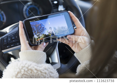 一名年輕女子在駕駛座上觀看雜耍視頻 111623738