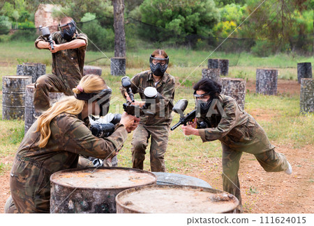Two active opposing teams with guns playing paintball Two active opposing teams with guns playing paintball 111624015