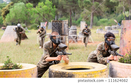 Couple of paintball players in camouflage playing paintboll outdoors Couple of paintball players in camouflage playing paintboll outdoors 111624082