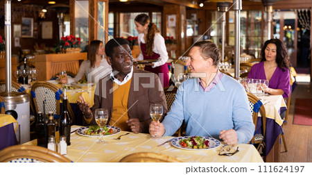 Friendly meeting of two men over dinner in restaurant 111624197