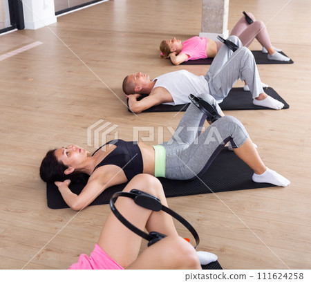 Group of adults exercising with pilates ring Group of adults exercising with pilates ring 111624258