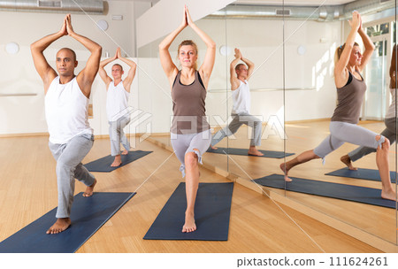 Man and woman performing Anjaneyasana during group yoga training 111624261