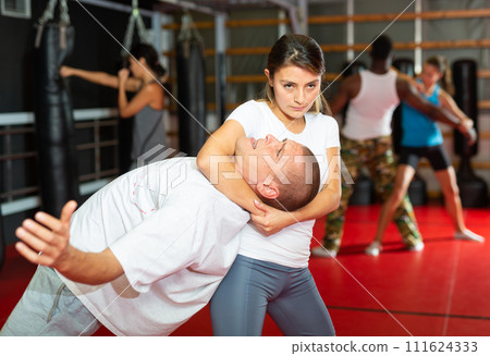 Woman exercising with man during group self-defence training 111624333
