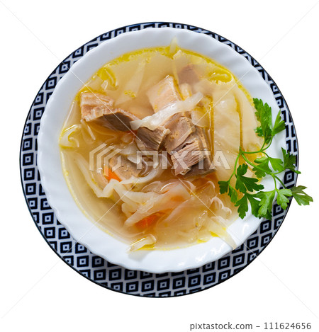 Deep plate with hot first course - hearty cabbage soup with large piece of bacon. 111624656