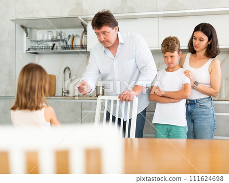At home in kitchen, parents scold their daughter for careless act 111624698