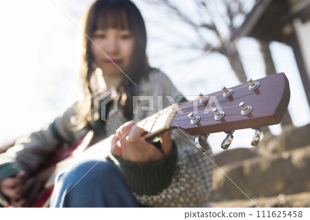 年輕女子在街上現場彈吉他 年輕女子在街上現場彈吉他 111625458