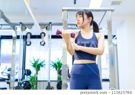 Young woman training her body at a personal gym, dumbbell curls, biceps, muscle training girl Young woman training her body at a personal gym, dumbbell curls, biceps, muscle training girl 111625769