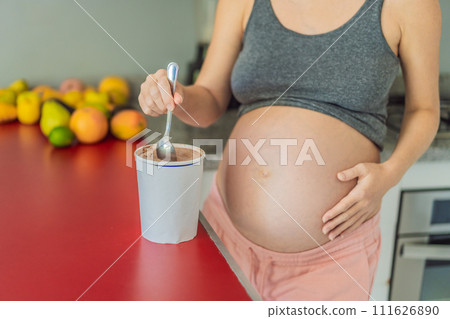 Happy pregnant young woman eating ice cream 111626890