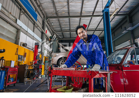 Portrait Asian Japanese male mechanic worker portrait in auto service workshop car maintenance center replace fix auto engine part 111628052