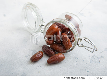 Glass jar with brown sweet dried dates on white kitchen background. 111628320