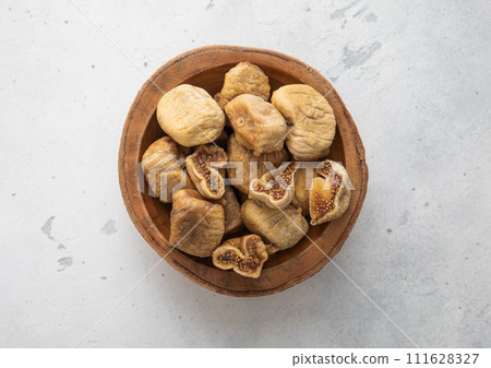 Wooden bowl of dried sweet white figs on light background. Wooden bowl of dried sweet white figs on light background. 111628327
