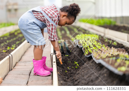 African black child playing planting the green tree gardening in agriculture farm. Children love nature concept. 111628331