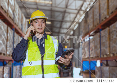 Warehouse worker using smartphone phone calling contact people in factory cargo storage area. 111628332