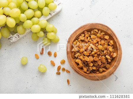 Green sweet dried raisins in wooden bowl on light background with ripe grapes. 111628381
