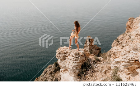Woman travel sea. Happy tourist enjoy taking picture outdoors for memories. Woman traveler looks at the edge of the cliff on the sea bay of mountains, sharing travel adventure journey Woman travel sea. Happy tourist enjoy taking picture outdoors for memories. Woman traveler looks at the edge of the cliff on the sea bay of mountains, sharing travel adventure journey 111628465