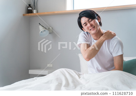 A young Asian man who suffers from stiff shoulders when he wakes up in the morning (fatigue, trouble sleeping, forty shoulders) 111628710