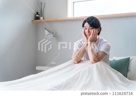 A man in his bedroom suffering from insomnia, lack of sleep, and sleep disorders 111628716