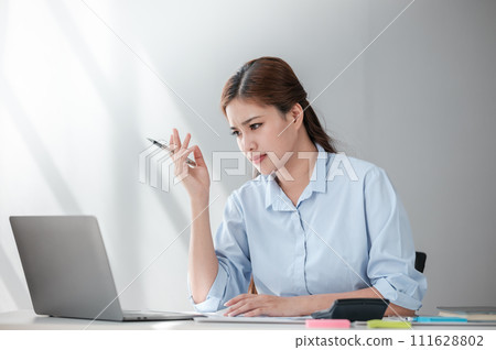Stressed out Asian Business woman using calculator and laptop for doing math finance on an office desk, tax, report, accounting, statistics, and analytical research concept Stressed out Asian Business woman using calculator and laptop for doing math finance on an office desk, tax, report, accounting, statistics, and analytical research concept 111628802