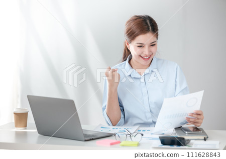 Cheerful Successful Asian Business woman using calculator and laptop for doing math finance on an office desk, tax, report, accounting, statistics, and analytical research concept Cheerful Successful Asian Business woman using calculator and laptop for doing math finance on an office desk, tax, report, accounting, statistics, and analytical research concept 111628843