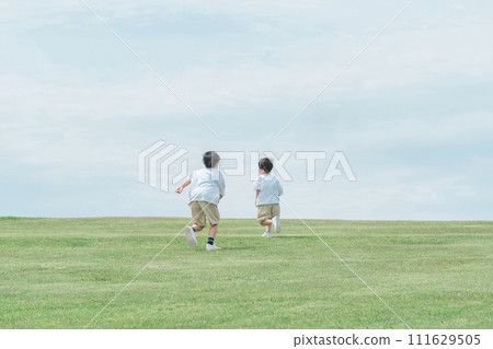 Active children, siblings, running chasing each other on a grassy hill Active children, siblings, running chasing each other on a grassy hill 111629505