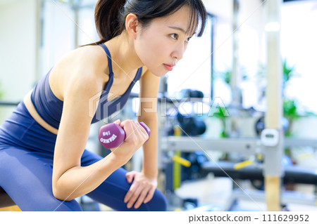 Woman training her body at the gym, dumbbell concentration curl, muscle training female workout Woman training her body at the gym, dumbbell concentration curl, muscle training female workout 111629952