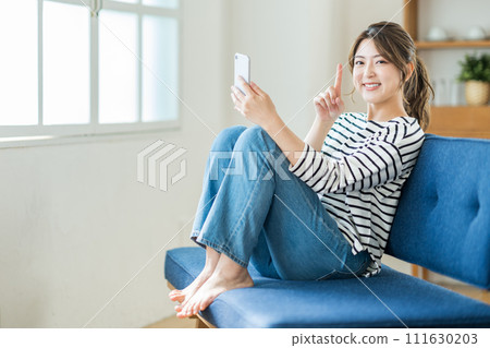 A young woman operating a smartphone. 111630203