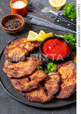 fried juicy pork steaks with ketchup on plate 111630921