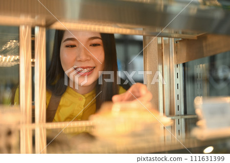Happy small pastry shop owner arranging pastry and cake in refrigerator showcase Happy small pastry shop owner arranging pastry and cake in refrigerator showcase 111631399