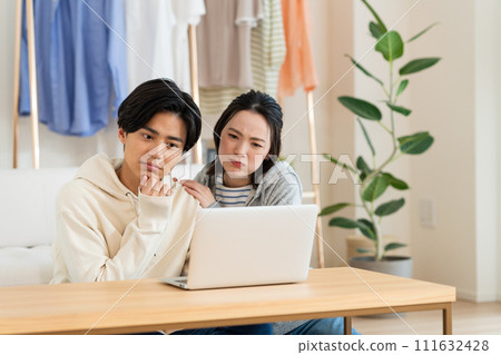 A young couple looking at a computer in the living room A young couple looking at a computer in the living room 111632428