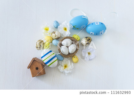 Happy easter holidays concept; Easter eggs, birdnest with eggs and flowers on a white background; top view Happy easter holidays concept; Easter eggs, birdnest with eggs and flowers on a white background; top view 111632993