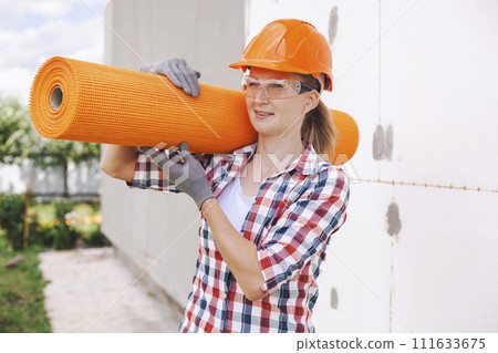 The woman with rolls of reinforcing fiberglass. Insulation of the house with polyfoam board on the facade 111633675