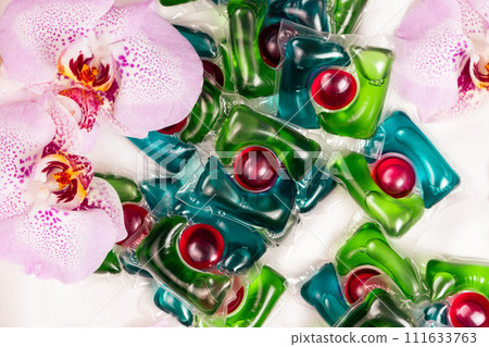 Laundry capsules among orchid flowers, close-up top view Laundry capsules among orchid flowers, close-up top view 111633763