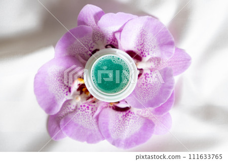Natural liquid laundry detergent with a floral scent on a background of satin fabric. Natural liquid laundry detergent with a floral scent on a background of satin fabric. 111633765